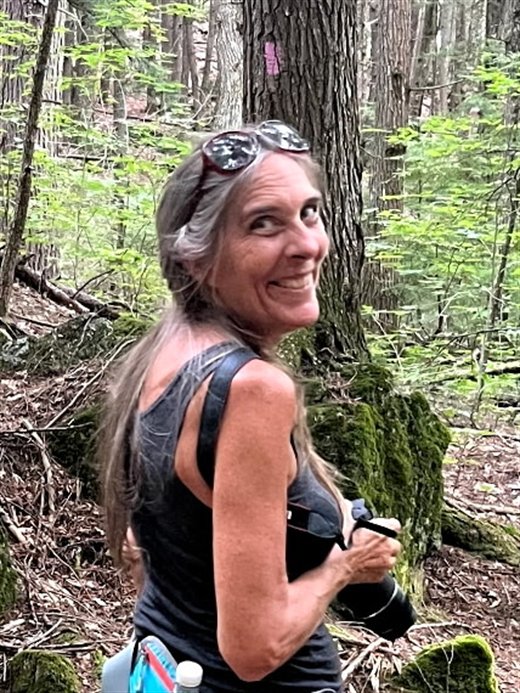 Stephanie Blaisdell, smiling, on a wooded trail.